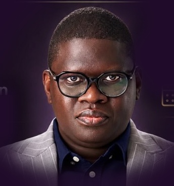 Dr. Stephen Akintayo, in a grey pinstripe jacket and glasses, looking directly at the camera.